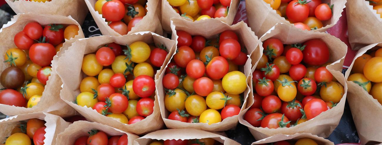 Small red and yellow tomatoes divided into paper bags